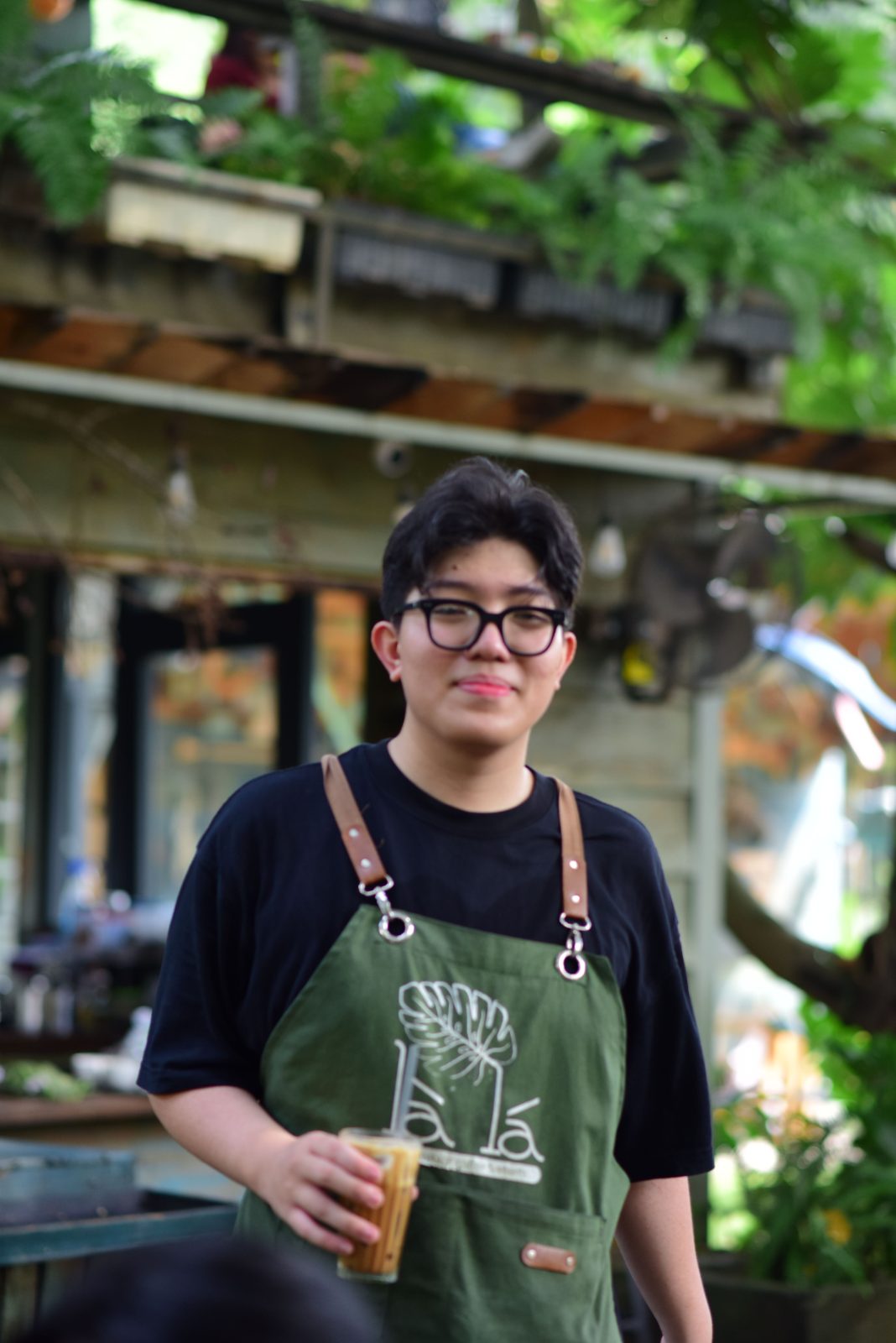 A smiling barista stands behind the counter of a newly opened café.