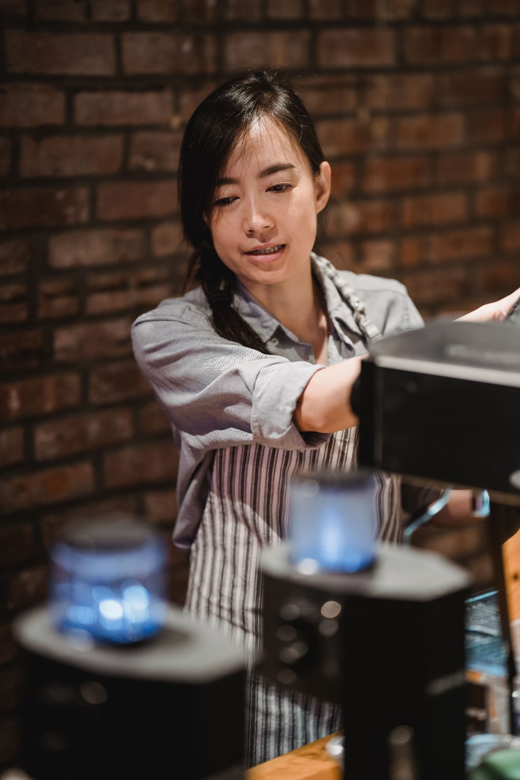 A café owner stands behind the coffee machine, thinking as she looks out at an empty shop.